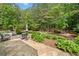 Lush backyard featuring a stone patio with outdoor seating and mature trees and landscaping at 295 River Laurel Way, Woodstock, GA 30188