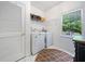 Bright laundry room features a washer, dryer, storage shelves, and a window with a view at 295 River Laurel Way, Woodstock, GA 30188