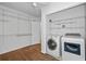 Bright laundry room with washer, dryer, hardwood floor, and adjustable wall shelving for optimal storage and organization at 4052 Shawnee Ne Ln, Brookhaven, GA 30319