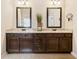 Elegant bathroom featuring dual sinks, granite countertops, dark wood cabinets, and stylish mirrors at 4779 Moon Hollow Ct, Buford, GA 30519