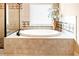 A luxurious white soaking tub is framed by tile and has a large window providing natural light at 4779 Moon Hollow Ct, Buford, GA 30519