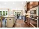 A large kitchen with stainless steel appliances, granite counters, dark wood cabinets and an island with barstool seating at 4779 Moon Hollow Ct, Buford, GA 30519