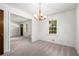 An open-concept dining room featuring a classic chandelier and neutral carpet at 4444 Bending River Sw Trl, Lilburn, GA 30047