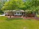 Charming single-story home with a brick facade, a lush green lawn, and mature trees providing shade at 4444 Bending River Sw Trl, Lilburn, GA 30047
