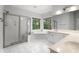 Bright bathroom with white tiled floors, shower, soaking tub, and a large window view at 710 Glen Royal Dr, Roswell, GA 30076