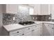 This kitchen has a stylish cooktop, mosaic backsplash, and ample storage space at 710 Glen Royal Dr, Roswell, GA 30076