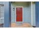 Close-up of the red front door featuring a stylish light fixture and light blue shingle siding at 7629 Park Ln, Jonesboro, GA 30236