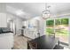Eat-in kitchen features white cabinets, modern light fixture, stainless steel appliances, and a sliding glass door at 7629 Park Ln, Jonesboro, GA 30236