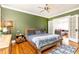 Comfortable bedroom with green walls, hardwood floors, ceiling fan, and view to living area with grey couch at 1125 Briarcliff Ne Pl # 14, Atlanta, GA 30306