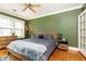Cozy bedroom features hardwood floors, green accent wall, a ceiling fan, and a wood-style bed with grey linens at 1125 Briarcliff Ne Pl # 14, Atlanta, GA 30306