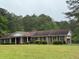 Charming single-story brick home with a cozy front porch and a lush green lawn surrounded by trees at 1935 Flat Shoals Se Rd, Conyers, GA 30013
