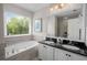 Bathroom with double vanity, granite countertops, tiled walls, large window, and a soaking tub at 925 Hill Se St, Atlanta, GA 30315