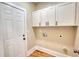 Bright laundry room with overhead cabinets, utility connections, white door and wood look flooring at 25 Oakbrook Ln, Covington, GA 30016