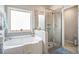 Bright bathroom features a large soaking tub, separate glass shower, and a window for natural light at 3399 In Bloom Way, Auburn, GA 30011