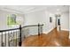 Upstairs hallway with hardwood floors, black railing, large window, and modern chandelier at 3925 Sheldon Ne Dr, Atlanta, GA 30342