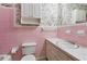 Retro pink bathroom featuring a vanity with sink, toilet, and floral wallpaper at 509 Woodland Ln, Lawrenceville, GA 30043
