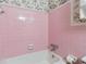 Pink tiled bathroom with a bathtub and a showerhead, complemented by floral wallpaper at 509 Woodland Ln, Lawrenceville, GA 30043