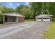 View of two garages, one carport and one detached with white doors and brick exterior, on a paved driveway at 509 Woodland Ln, Lawrenceville, GA 30043
