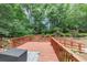 Backyard with a red wooden deck, lush foliage, and mature trees at 115 Blue Ridge Trl, Powder Springs, GA 30127