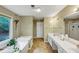 Bathroom featuring double sinks, a soaking tub, and a view of nature from the large window at 115 Blue Ridge Trl, Powder Springs, GA 30127