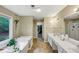 Bright bathroom featuring double sinks, a soaking tub, and a view of nature from the large window at 115 Blue Ridge Trl, Powder Springs, GA 30127