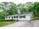 Charming single-story home featuring a long driveway, well-kept yard, and classic black and white exterior paint at 2923 Bicentennial Dr, Stone Mountain, GA 30087