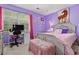Bedroom with purple walls, a cozy bed, a desk, and a window providing ample natural light at 1767 Hunters Sw Trce, Lilburn, GA 30047