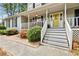 Inviting front porch with white railings, lush landscaping, and a bright yellow front door at 1767 Hunters Sw Trce, Lilburn, GA 30047