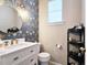Stylish half bathroom featuring modern wallpaper, a vanity with a round mirror and marble countertop, and decorative accents at 3811 Holliwell Pass, Cumming, GA 30040