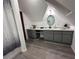 An attic bathroom with gray cabinets, wood flooring, and a unique round mirror at 4220 Chapel Hill Farms Dr, Douglasville, GA 30135