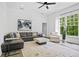 Bright living room featuring a modern ceiling fan, large windows, and a stylish gray leather sofa at 4356 N Buckhead Ne Dr, Atlanta, GA 30342