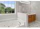 Bright bathroom showcasing a large jacuzzi tub, white cabinets, and natural light from the adjacent window at 406 Mount Vernon Ct, Woodstock, GA 30189