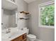 Bathroom featuring a sink with wooden cabinets, a toilet, shelves, and a shower with natural light through the window at 406 Mount Vernon Ct, Woodstock, GA 30189
