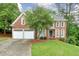Charming two-story brick home featuring a well-manicured lawn, mature trees, and a two-car garage at 305 High Branch Way, Roswell, GA 30075