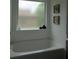 Bright bathroom featuring a soaking tub, frosted window, and decorative wall art at 4832 Batiste Nw Ln, Acworth, GA 30101