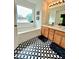 Well-lit bathroom featuring wood cabinets with double sinks, black and white geometric flooring, and a bathtub at 4832 Batiste Nw Ln, Acworth, GA 30101