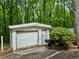 Detached garage with white siding and a double wide door surrounded by green forest at 1720 Valley Ln, Cumming, GA 30040