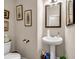 Elegant half bath featuring a pedestal sink, decorative mirror, and stylish wall art at 255 Skipjack Ct, Covington, GA 30016