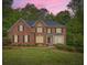 Brick home with a well-manicured lawn and lush landscaping under a pink sky at 3801 Bays Ferry Trl, Marietta, GA 30062