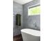 Modern bathroom featuring a soaking tub next to a window with natural light and stylish gray tiling at 1378 Lochland Se Rd, Atlanta, GA 30316