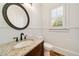 Elegant powder room with granite countertop, dark fixtures, decorative mirror and natural light at 2017 Harts Mill Ne Rd, Chamblee, GA 30341
