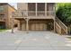 View of a three car garage, with overhead deck and a staircase to the right of the garage at 2017 Harts Mill Ne Rd, Chamblee, GA 30341