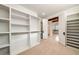 Well-organized walk-in closet leading to bathroom with custom shelving, wooden beams, and neutral carpet at 2017 Harts Mill Ne Rd, Chamblee, GA 30341