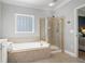 Bathroom featuring a soaking tub, a glass enclosed shower, and beige tile at 5375 Glenhaven Dr, Cumming, GA 30041