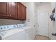 Well-equipped laundry room with a side-by-side washer and dryer, dark wood cabinets, and tile floors at 5375 Glenhaven Dr, Cumming, GA 30041