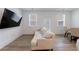 Living room with white couch, TV, light hardwood floors, and plenty of natural light at 1624 Gunnin Nw Trce, Atlanta, GA 30318
