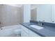 Bathroom vanity featuring gray countertop and a tiled bathtub and shower at 5623 Meadowstone Walk, Kennesaw, GA 30152