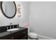 Stylish powder room with a dark vanity, granite countertop, round mirror, and decorative wall sconce at 610 Valley Green Trce, Marietta, GA 30068