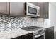 Features stainless steel appliances, dark cabinets, and mosaic backsplash for a modern kitchen look at 610 Valley Green Trce, Marietta, GA 30068