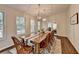 Elegant dining room with chandelier lighting, rustic table, and many windows at 443 Lakeshore Dr, Berkeley Lake, GA 30096
